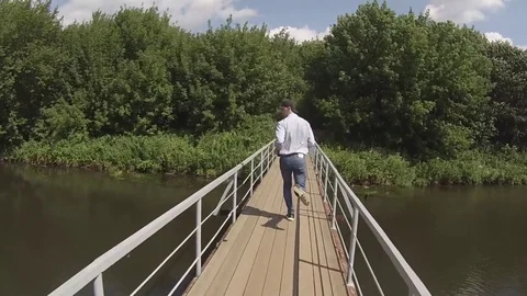 A man runs across the bridge in the summer field Stock Footage 79028480
