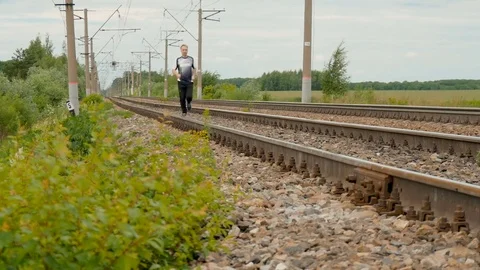 Man runs between rails on railroad tracks. Video stock 77338239