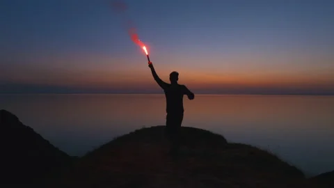 The man runs with a burning fire stick on the seascape background. slow motion Video stock 143570733