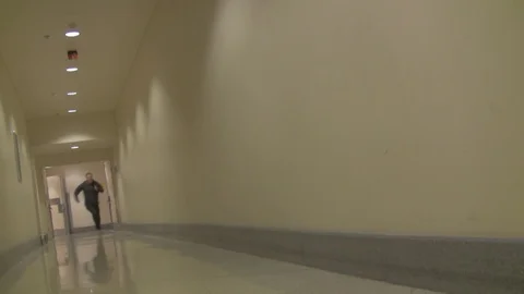 A man runs down a hallway long shot2 Stock Footage 99610951