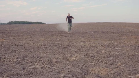 MAN RUNS ON DRIED FIELD. CONCEPT ON THE THEME OF DRAFT 스톡 동영상 128090663