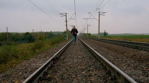 Man runs on railroad tracks Stock Footage