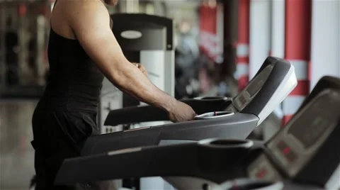 A man runs on a running machine in the gym Stock Footage 56636013
