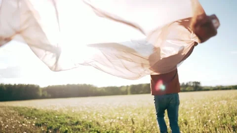 A man runs through a field with a transparent cloth Curtains flutter in the wind Stock Footage 154764536