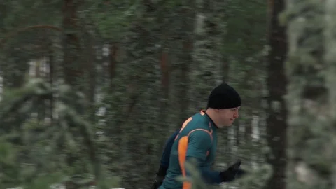 A man runs through the winter forest snow around Stock Footage 129639223
