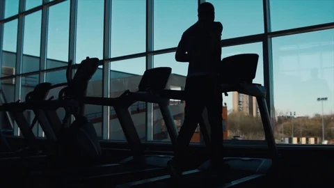 Man runs on a treadmill on a window background 스톡 동영상 88830106