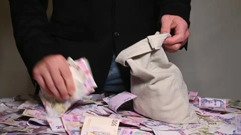 Man in rush stuffs sack with bundles of Ukrainian currency, hryvnia. Stock Footage 342244833