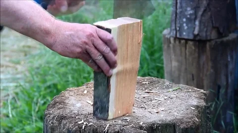 Man s hand holding an ax and chopping a small piece of wood into thin kindlin Stock Footage 77587887