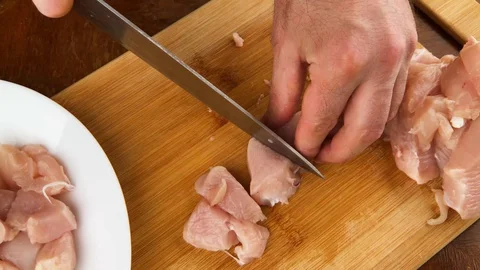 Man s hands with knife slices delicate chicken fillet on cut board. Stock Footage 130105816