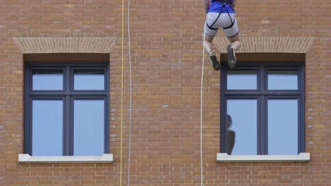 Man in Safety Harness Abseiling Down Brick Building Facade. Stock Footage 340501569