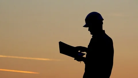 Man  with safety helmet take notes close sunset sky, engineer write on the map Vidéo 89889173