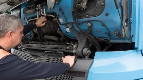 Man with safety vest checking engine parts of a european truck. Stock Photos
