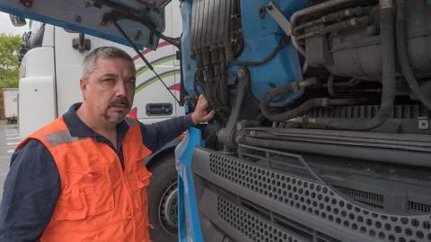 Man with safety vest checking engine parts of a european truck. Stock Photos