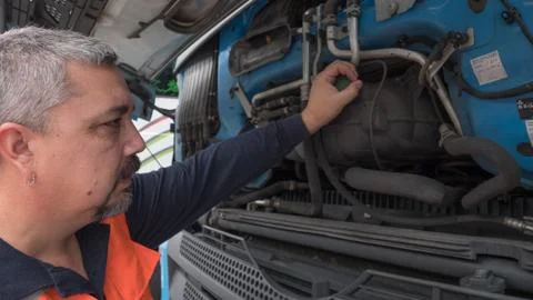 Man with safety vest checking engine parts of a european truck. Stock Photos