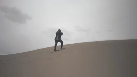 Man Sand Boarding on Big Dune While Throwing Color Powder in Super Slow Motion Stock Footage 142341236
