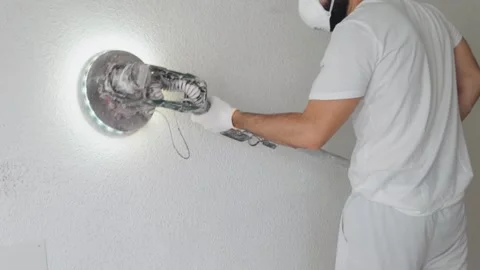 Man Sanding A White Wall With Electric Orbital Sander And LED 库存影片 343571118
