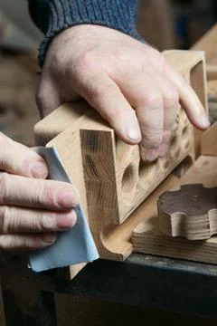 Man sandpaper grinds wood product in one studio Stock Photos