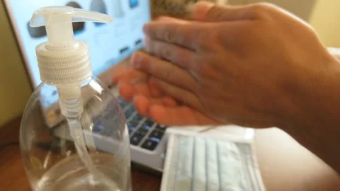 Man sanitizing hand with alcohol gel while working on laptop,covid19 pandemic 4k Stock Footage 142565641