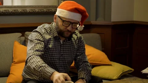 Man with santa cap sitting on the sofa and giving somethink  Stock Footage 60663161