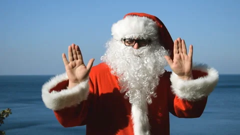 A man in a Santa Claus costume is dancing on the seashore. Travel and vacation Stock Footage