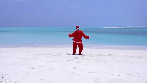 Man in Santa Claus Hat dancing on sandy beach. Christmas vacation Stock Footage 82917880