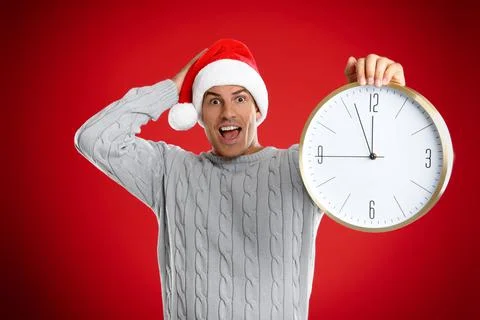 Man in Santa hat with clock on red background. New Year countdown 스톡 사진