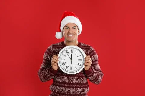 Man in Santa hat with clock on red background. New Year countdown 스톡 사진
