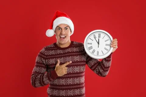 Man in Santa hat with clock on red background. New Year countdown 스톡 사진