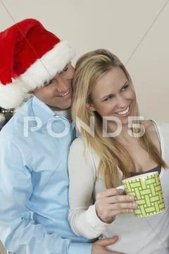 Man In Santa Hat Embracing Woman Holding Coffee Cup Stock Photos