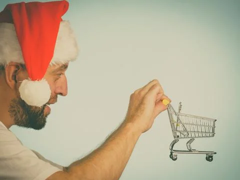Man in santa hat holds empty shopping cart Stock Photos