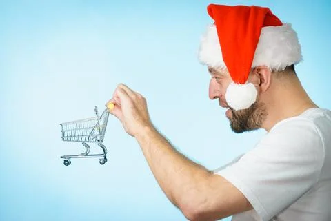 Man in santa hat holds empty shopping cart Stock Photos