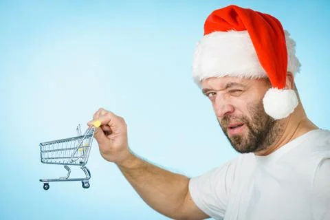 Man in santa hat holds empty shopping cart Stock Photos