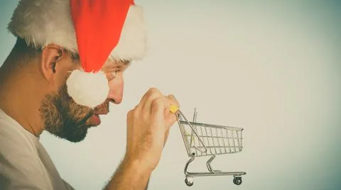 Man in santa hat holds empty shopping cart Stock Photos