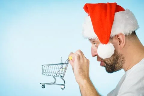 Man in santa hat holds empty shopping cart Stock Photos