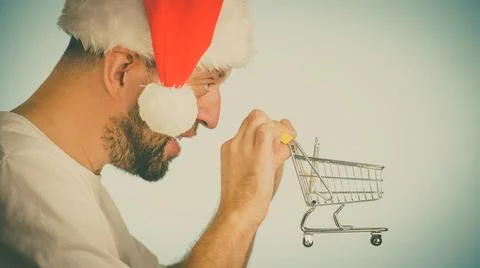 Man in santa hat holds empty shopping cart Stock Photos