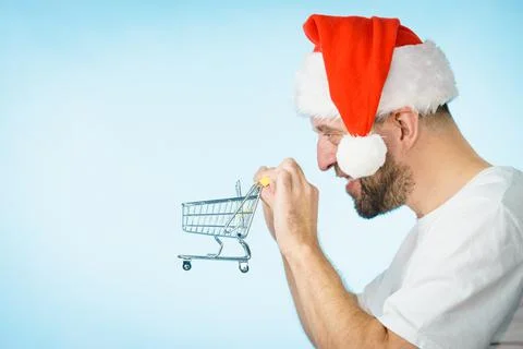 Man in santa hat holds empty shopping cart Stock Photos