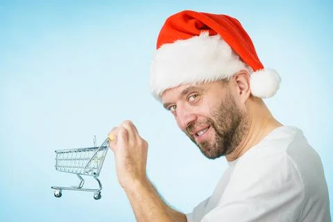 Man in santa hat holds empty shopping cart 스톡 사진