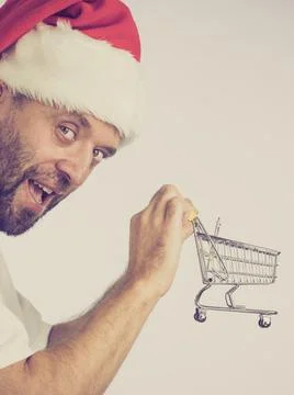 Man in santa hat holds empty shopping cart Stock Photos