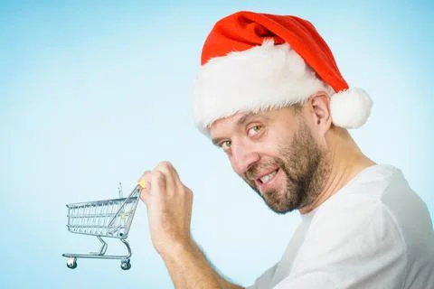 Man in santa hat holds empty shopping cart Stock Photos