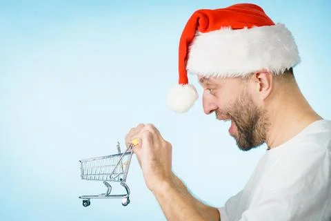 Man in santa hat holds empty shopping cart Stock Photos