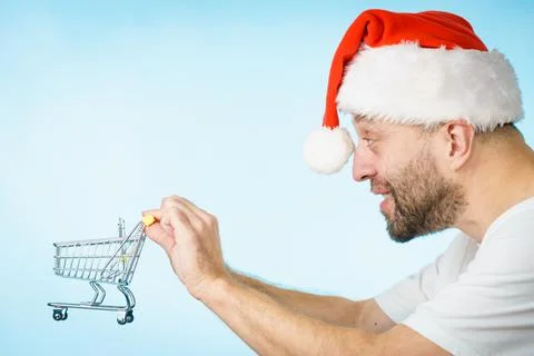 Man in santa hat holds empty shopping cart Stock Photos