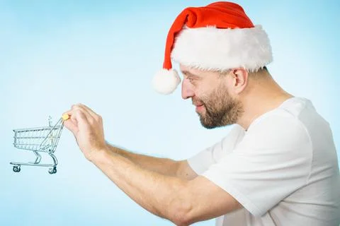 Man in santa hat holds empty shopping cart Stock Photos