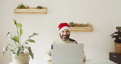 Man with Santa hat making a video call with laptop from an office Stock Footage 144984662