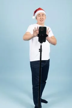 Man in Santa Hat Posing Behind Smartphone Tripod Foto stock