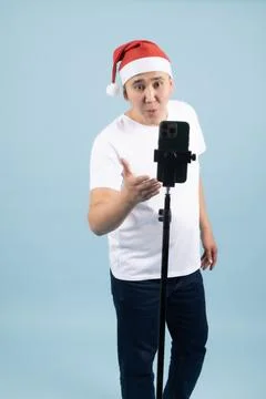 Man in Santa Hat Recording Video on Smartphone Foto stock