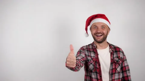 A man in a Santa hat shows a copy space and shows approval with your thumb Vídeos de archivo 144258688