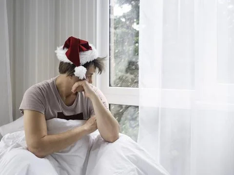 Man in Santa hat is waking up after Christmas party. He is suffering of heada Stock Photos