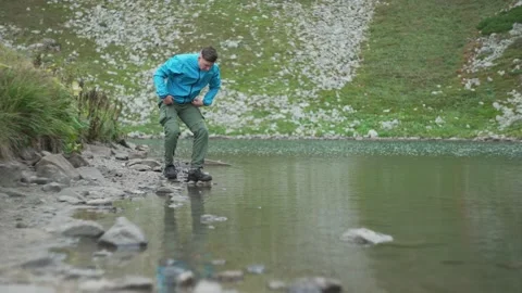 The man sat down on the shore of the lake to wash his face. Water splashes Stock Footage 218442053