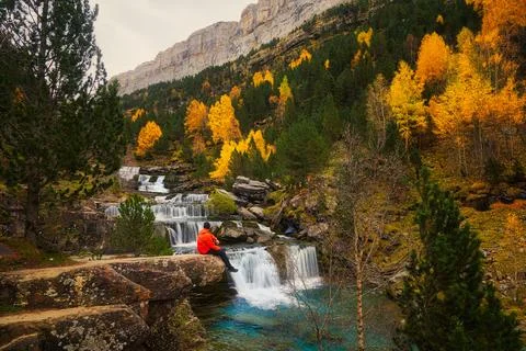 Man sat on a rock looking back at waterfalls Stock Photos