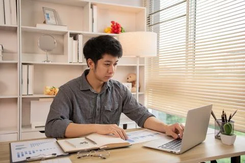 Man sat typing away on a laptop in his office with a determined look on his f Stock Photos